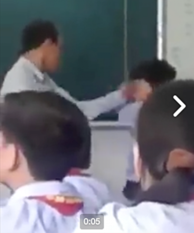 Giám thị tát liên tiếp vào mặt nam sinh ngay trên bục giảng (Ảnh cắt từ clip).