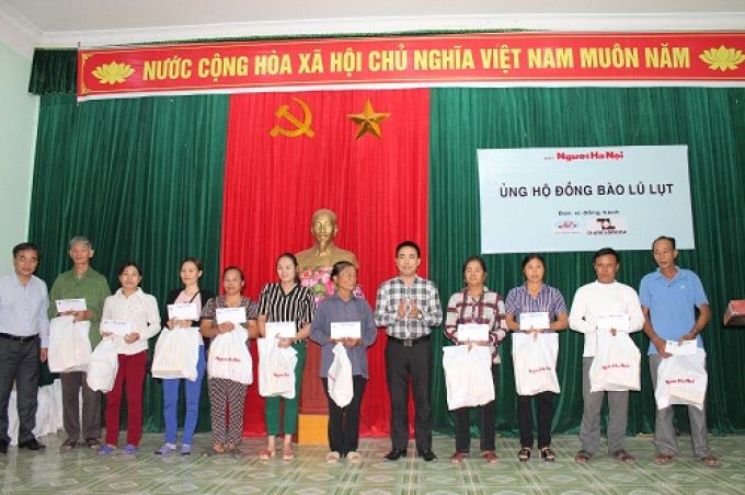 Nh&agrave; b&aacute;o Đ&agrave;o Xu&acirc;n Hưng - Tổng Bi&ecirc;n tập B&aacute;o Người H&agrave; Nội (đứng giữa) v&agrave; &ocirc;ng Ng&ocirc; B&aacute; Quyết - C&ocirc;ng ty Thăng Long tặng qu&agrave; cho b&agrave; con v&ugrave;ng lũ x&atilde; Hữu Văn, huyện Chương Mỹ.